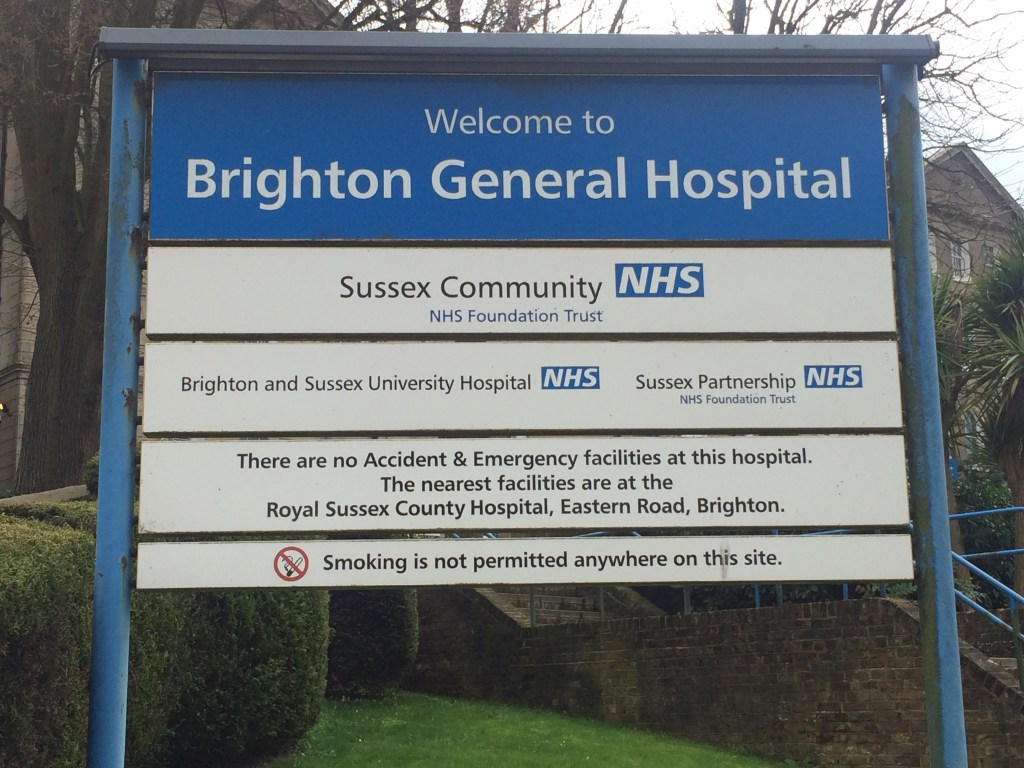 A large sign outside Brighton General Hospital, stating that it is the location of Sussex Partnership NHS Foundation Trust.
