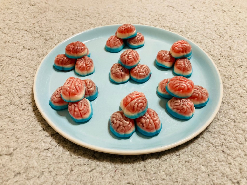 Many brain-shaped gummy sweets stacked in pyramid shapes on a round plate